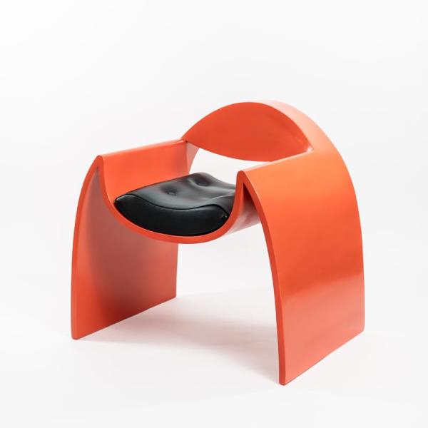 Изогнутое кресло с ярко-оранжевой отделкой.