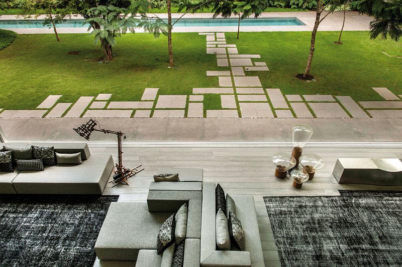 Квадратные бетонные брусчатки, расположенные геометрически на заднем дворе этого современного дома, создают характерную дорожку.