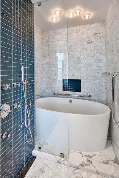 Современная ванная комната с белой ванной, серой мраморной плиткой метро, ​​душем и нишей для стеллажей, выложенной квадратной бирюзовой плиткой.