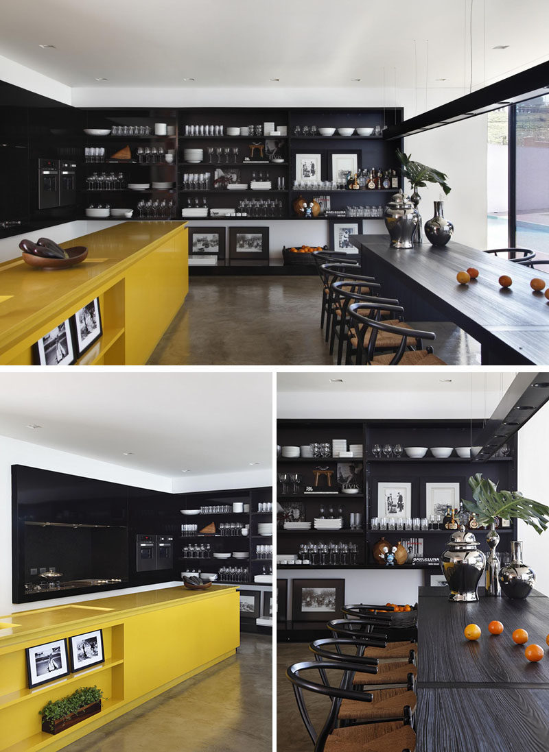 Желтый кухонный остров ярких красок к черной мебели и полкам на остальной кухне 