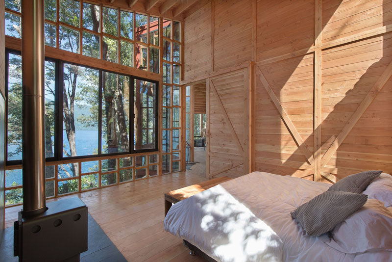 Эта спальня с небольшим камином позволяет максимально использовать вид благодаря окнам от пола до потолка.