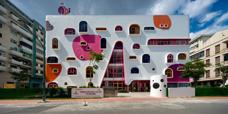 Идеи фасада - Белый фасад детского сада отличается яркими акцентами, которые дополняют красочные оконные рамы геометрической формы. #FacadeIdeas # Архитектура #UniqueWindowShapes