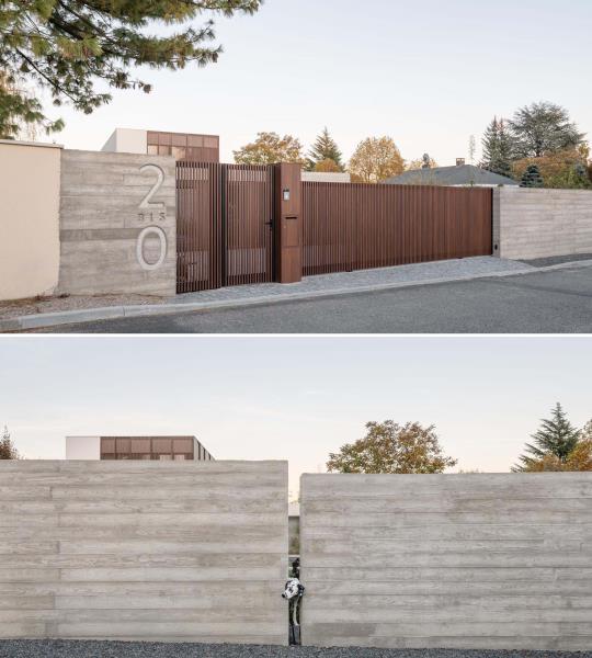 Современная бетонная передняя стена с деревянными воротами и подъездом.