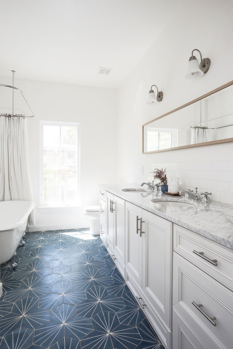 Голубая плитка в виде одуванчика добавляет яркости этой современной белой ванной комнате. #BlueTile #BathroomDesign