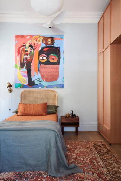 Спальня с ярким и ярким произведением искусства над кроватью.
