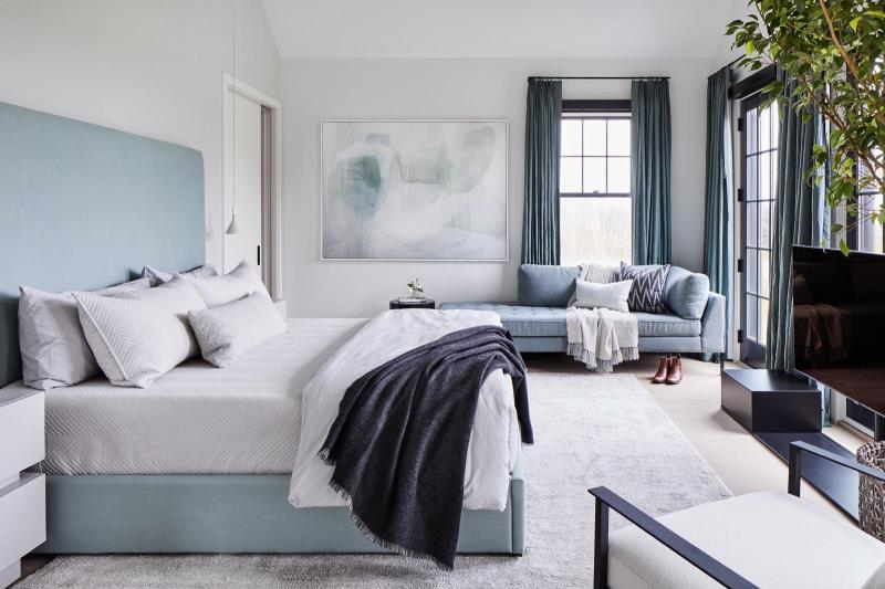 Залитая солнцем главная спальня оформлена в успокаивающей голубой цветовой палитре, вдохновленной природой дома.
