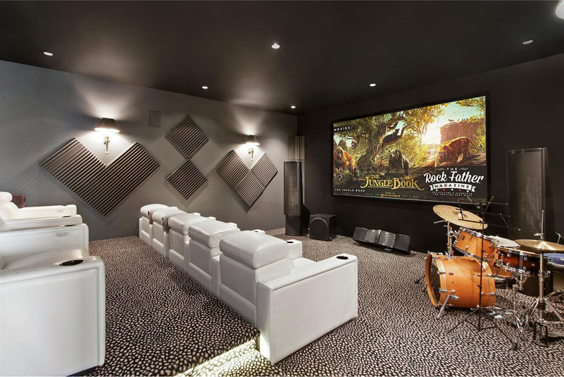 В этой комнате домашнего кинотеатра есть многоярусные белые шезлонги, которые идеально подходят для просмотра фильмов.