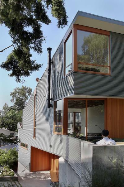 Дом с гофрированным металлическим сайдингом и деревянными оконными рамами.