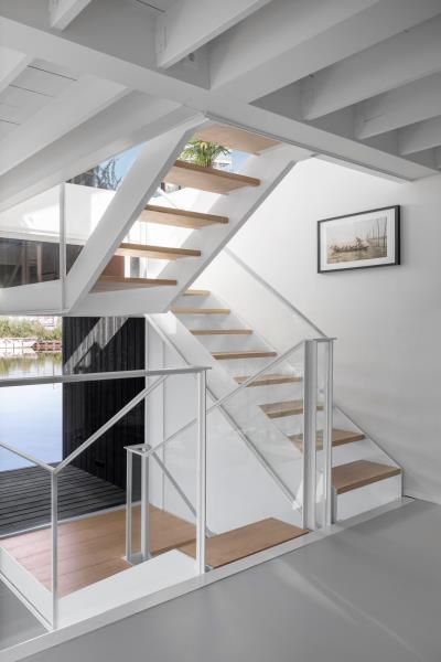 Белая лестница в этом современном плавучем доме сочетается со стенами и потолком, соединяет различные уровни плавучего дома и добавляет в пространство теплый деревянный элемент.