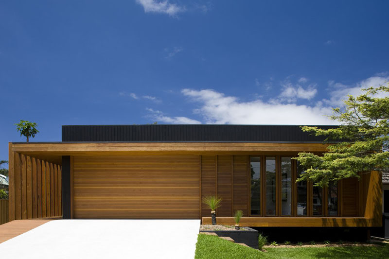 18 вдохновляющих примеров современных гаражных ворот // Тонкие горизонтальные деревянные панели покрывают гараж и остальную часть фасада этого дома, обеспечивая бесшовную интеграцию в экстерьер.
