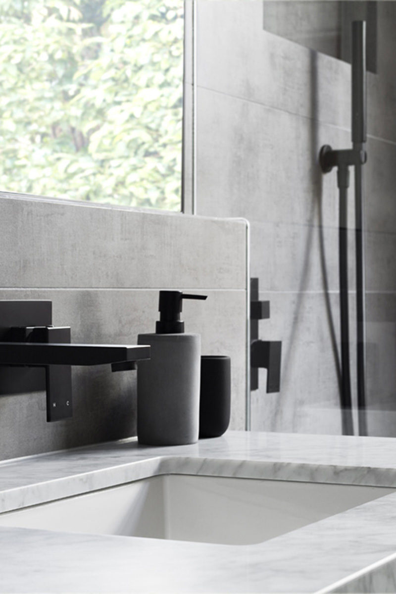 В этой современной серо-белой ванной комнате матовые черные акценты, такие как мыльные насосы и фурнитура, добавляют ванную комнату изысканности.