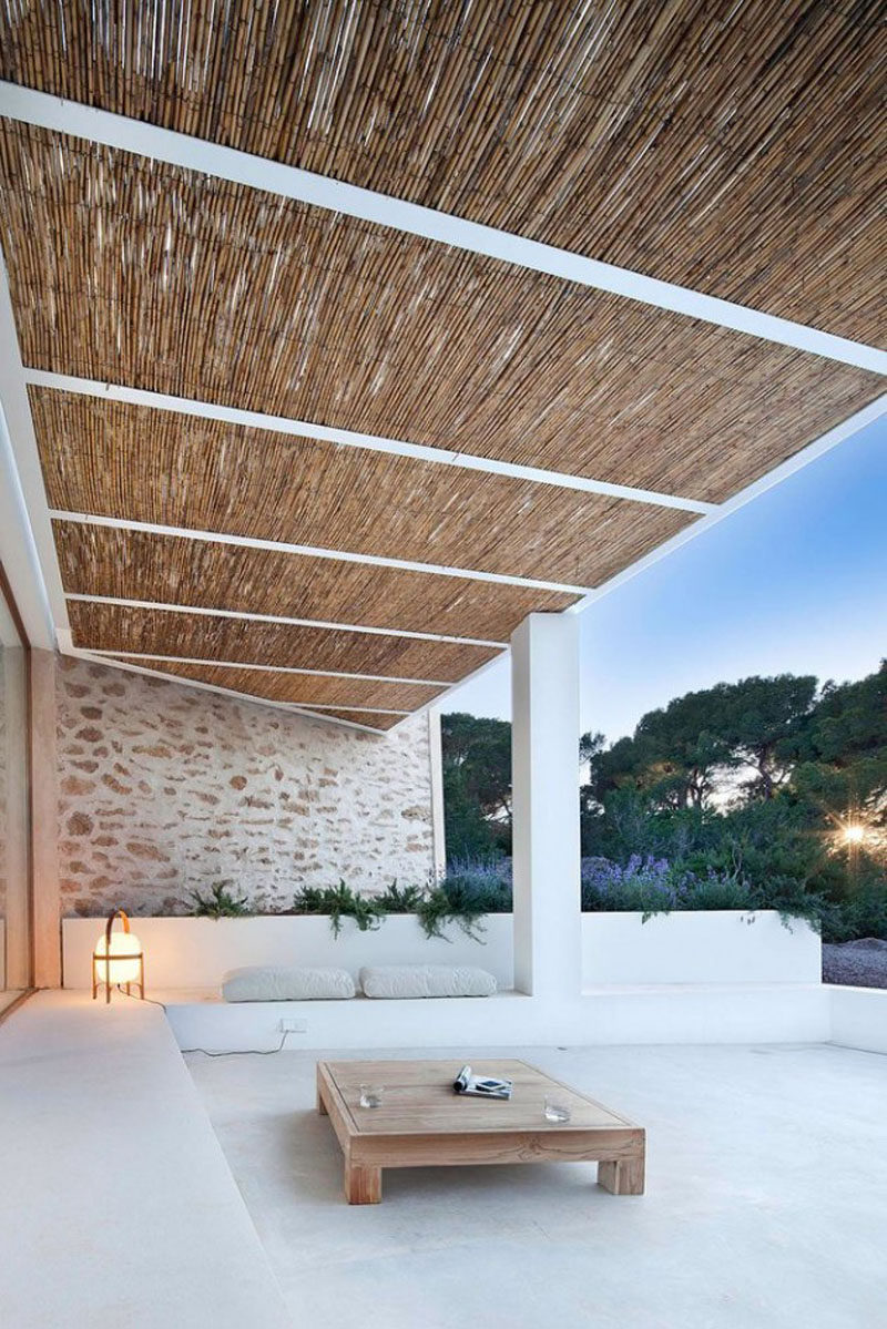 Это расслабляющее крытое открытое пространство со встроенными креслами , светлой каменной стеной и бамбуковой крышей 