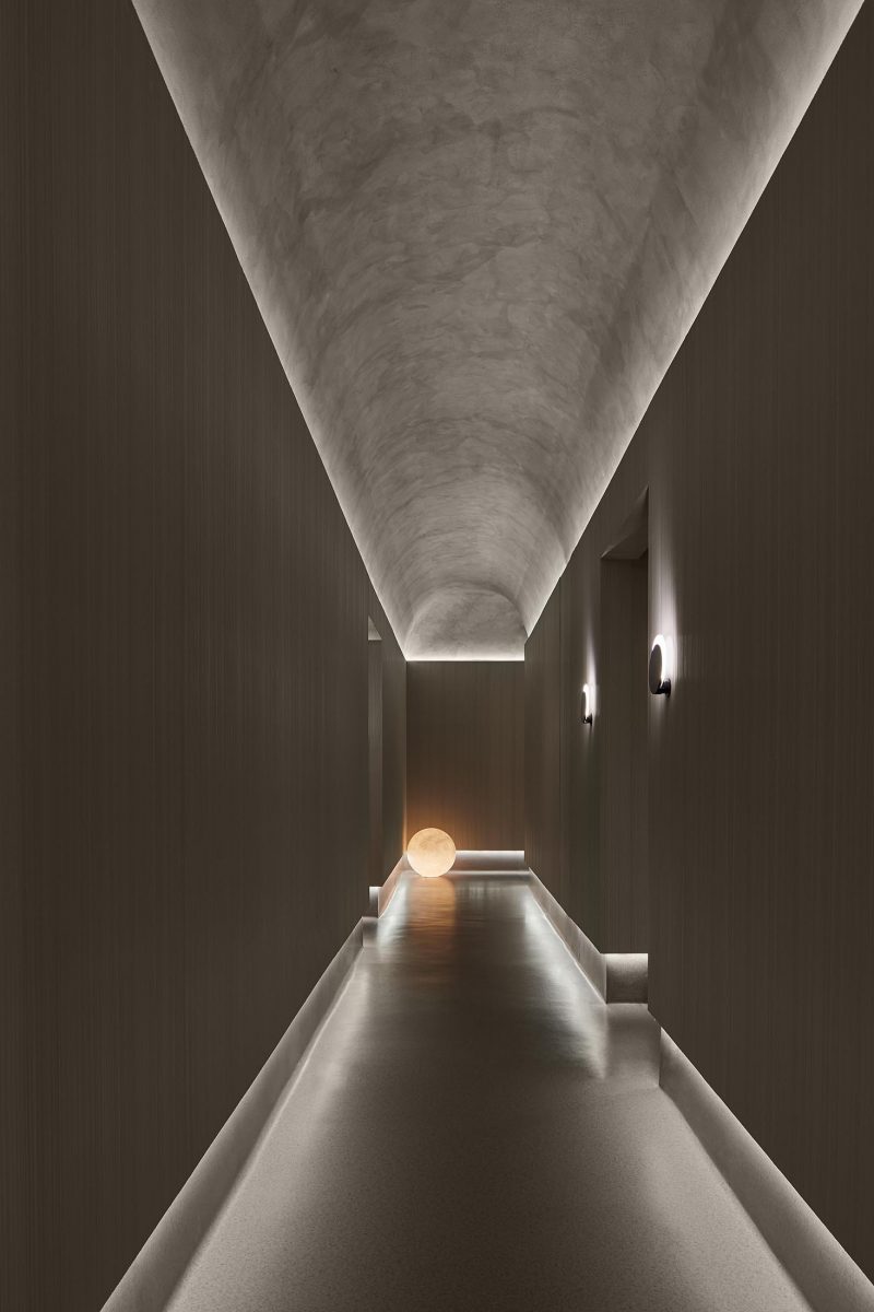 Непрямое освещение подчеркивает изогнутый потолок и пол в этом коридоре.