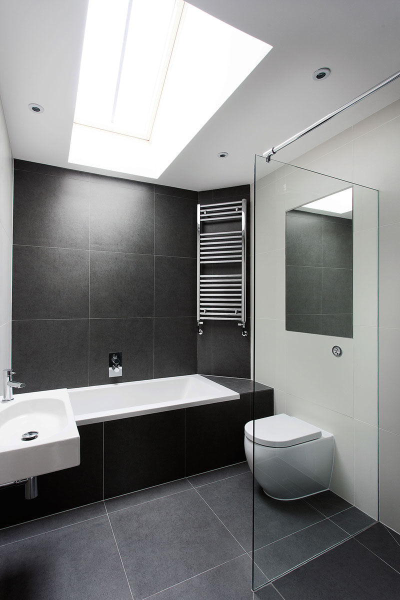 Идеи плитки для ванной комнаты - используйте большую плитку на полу и стенах // Большая черная каменная плитка в этой ванной комнате помогает создать простую черно-белую цветовую схему, а свет от потолочного окна делает ванную комнату более высокой и открытой.