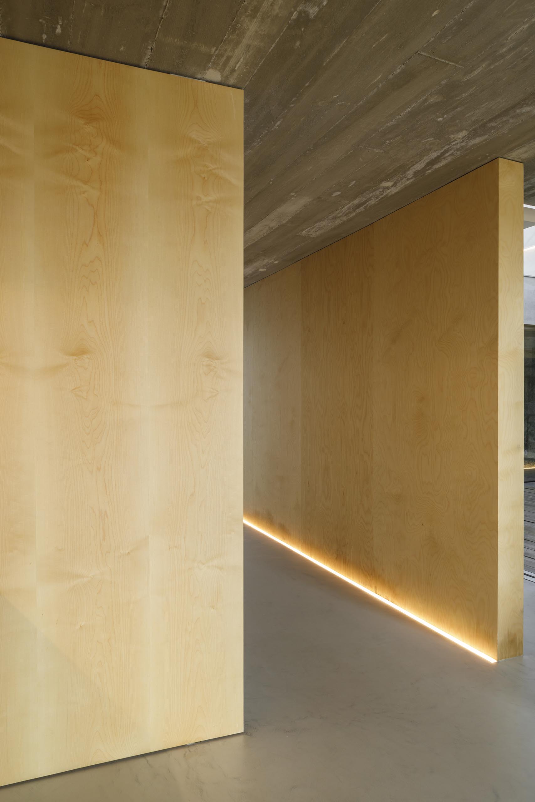Коридор с деревянными стенами освещен светодиодной подсветкой на полу.