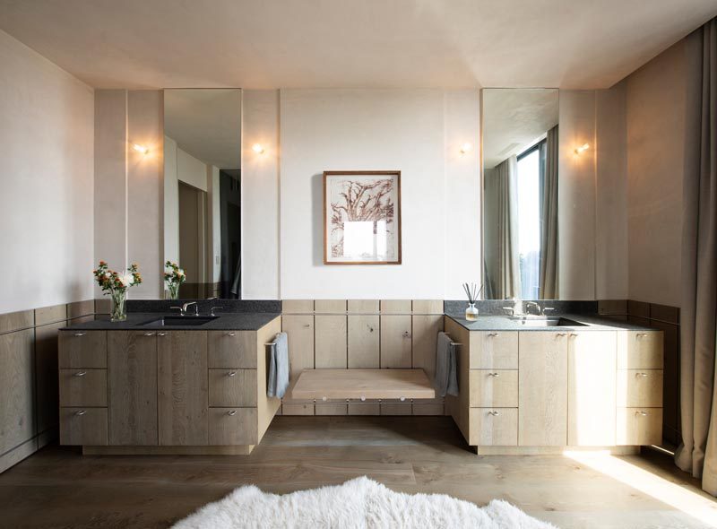 В этой современной главной ванной комнате два деревянных умывальника разделены небольшой скамейкой, а деревянная обшивка была использована для добавления уникального элемента дизайна в пространство. # МастерВанная # ВаннаяДизайн