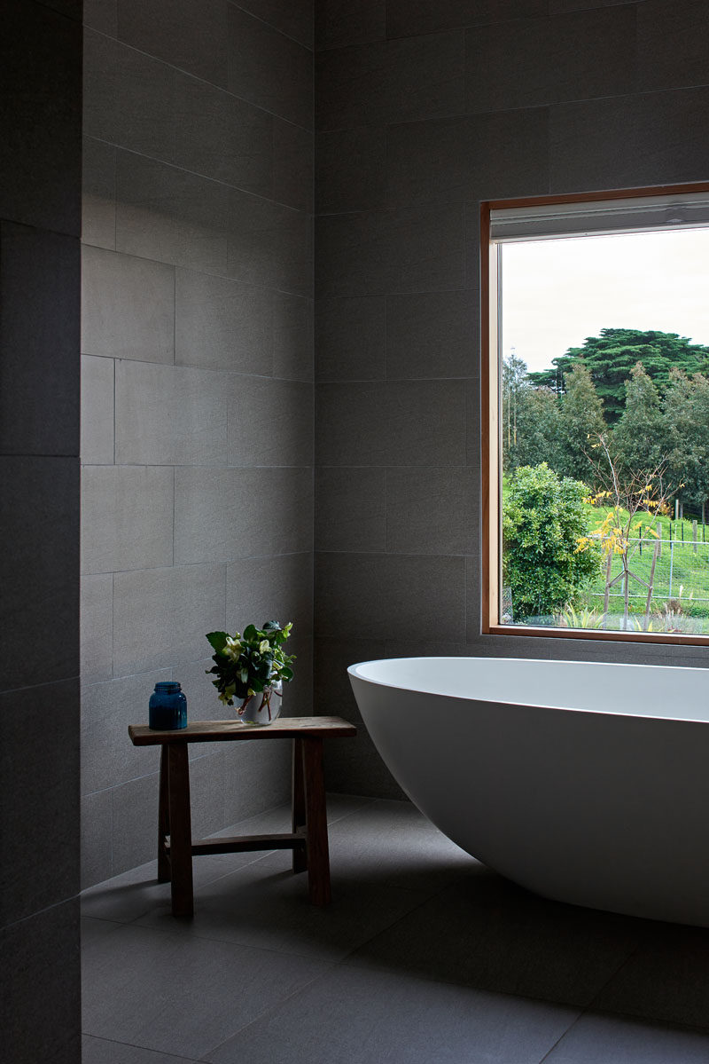 В этой современной ванной комнате большая серая плитка сочетается с деревянными оконными рамами и белой ванной, что придает ей современный вид. # СераяВанная # СераяПлитка # СовременнаяВанная #Дизайн ванной