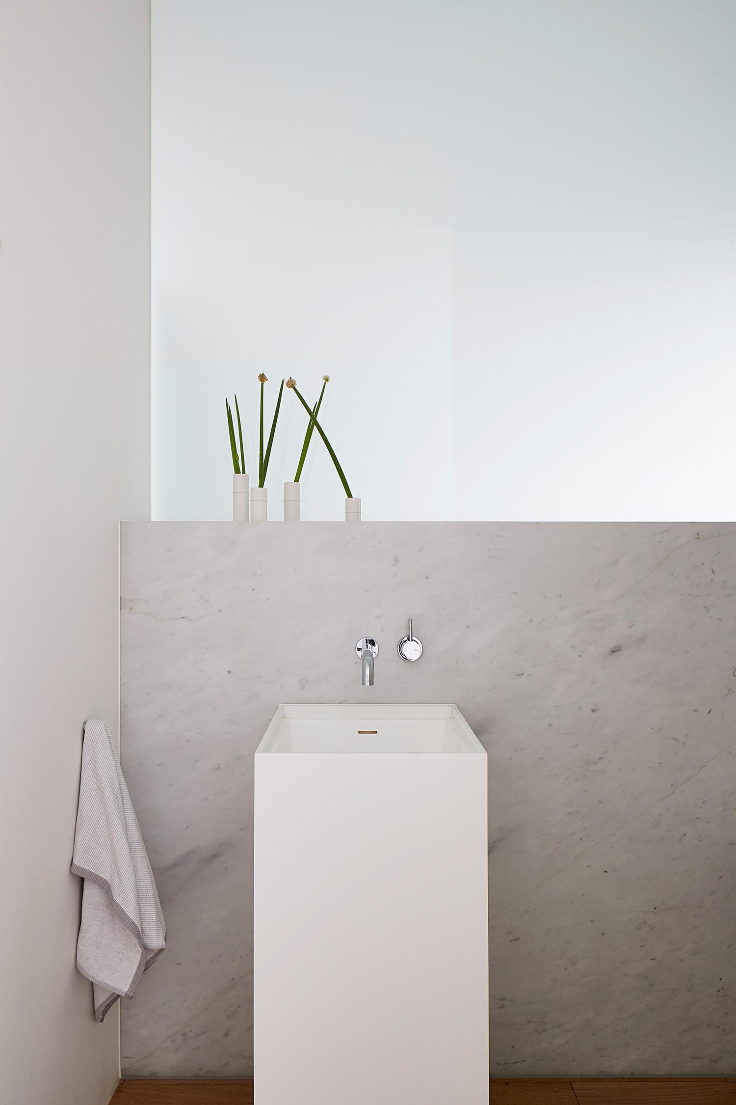 Современная ванная комната с нейтральной цветовой палитрой и современной белой раковиной на пьедестале.