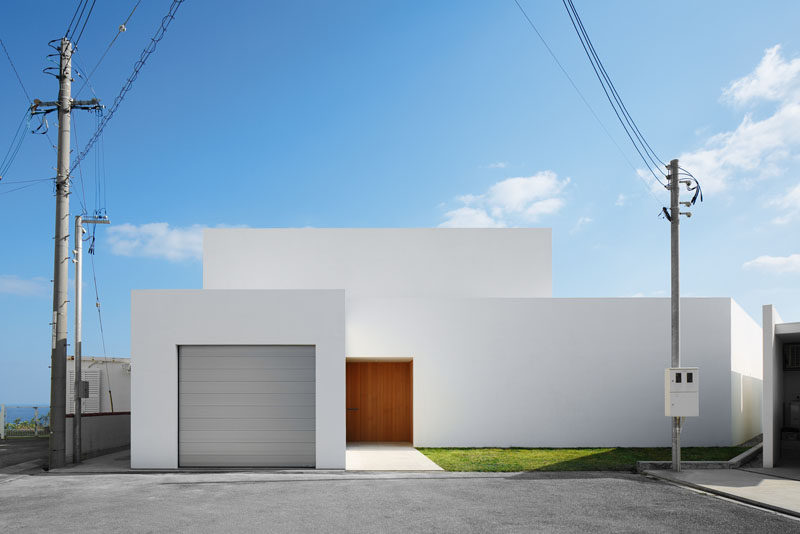  12 Минималистский внешний вид современного дома // Простой белый минималистский дом с серой гаражной дверью и деревянной входной дверью придает дому современный вид и согревает весь белый экстерьер. 