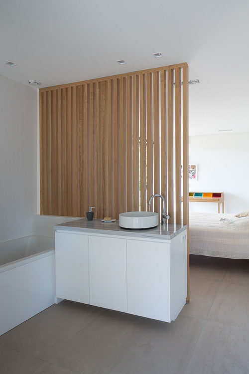 Эта ванная комната отделена от кровати деревянной решетчатой ​​стеной.