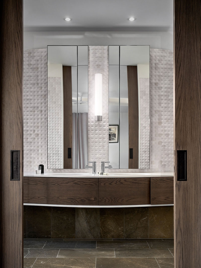 В этой современной ванной комнате на заказ деревянный туалетный столик резко контрастирует с мраморной плиткой, а зеркала делают пространство больше. # Ванная # Мраморная плитка # WoodVanity