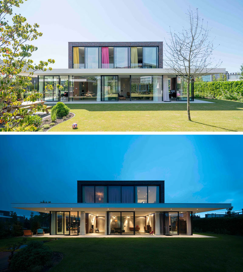 В задней части этого дома большие раздвижные стеклянные двери и окна открывают доступ внутрь дома, позволяя естественному свету заливать пространство 