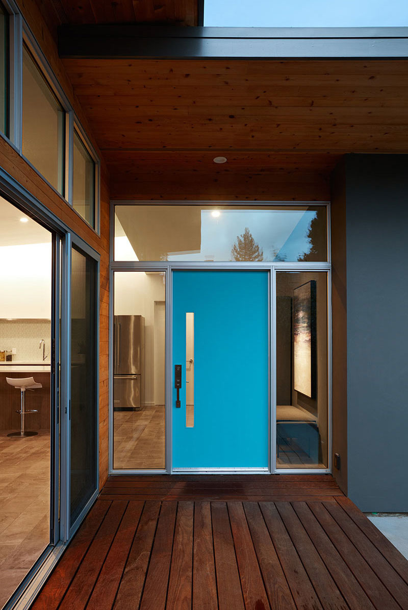 Голубая дверь этого дома обрамлена стеклянными окнами, благодаря чему вход в этот современный дом выглядит больше.