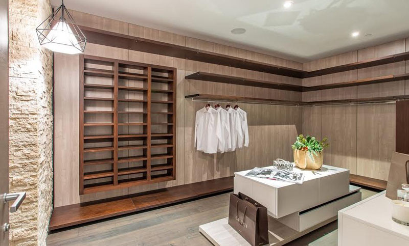 В этой гардеробной есть множество деревянных шкафчиков и полок, а также центральный островок для хранения ваших аксессуаров. 