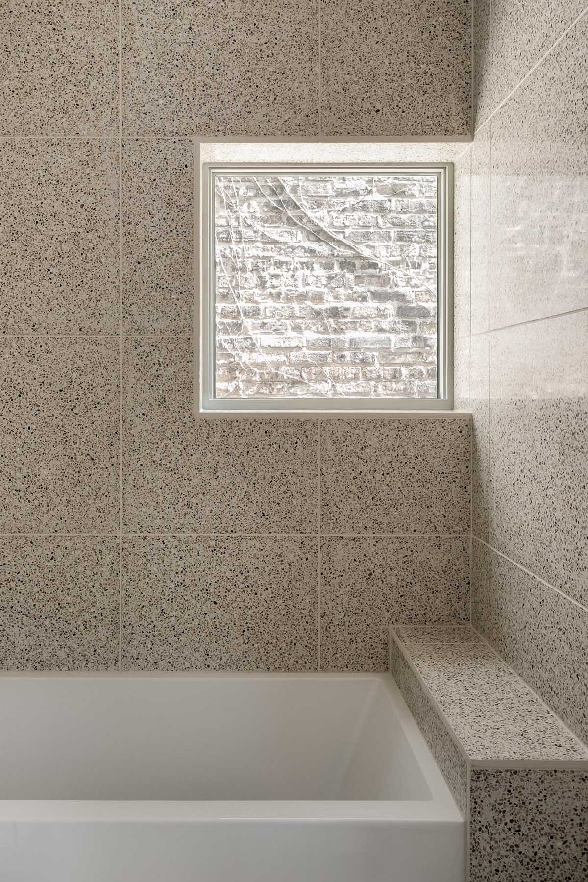 Эта современная ванная комната отделана плиткой большого формата и оснащена встроенной ванной.