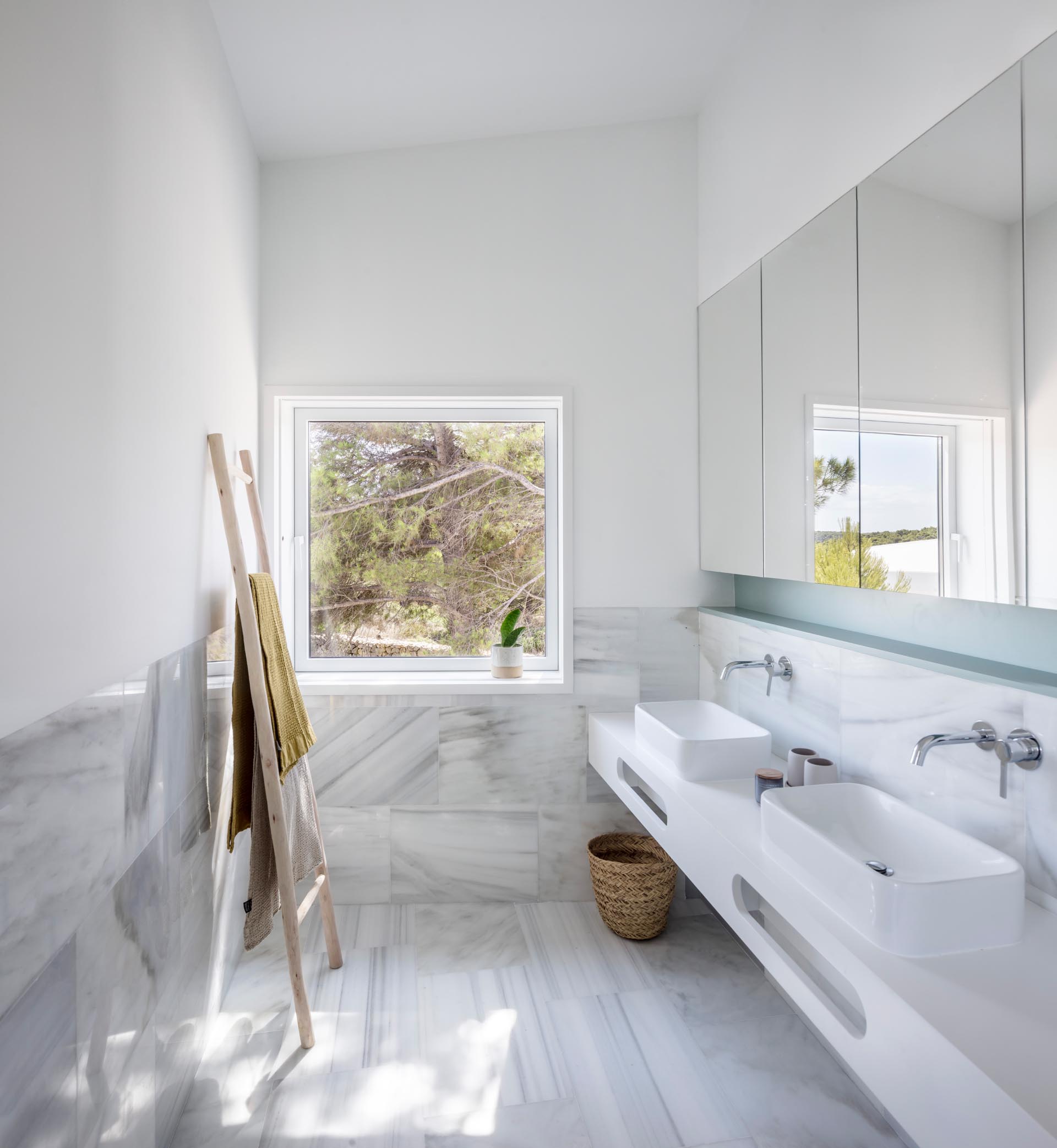 Современная ванная комната с мраморной плиткой большого формата, белым туалетным столиком и нишей стеллажа пастельно-бирюзового цвета.