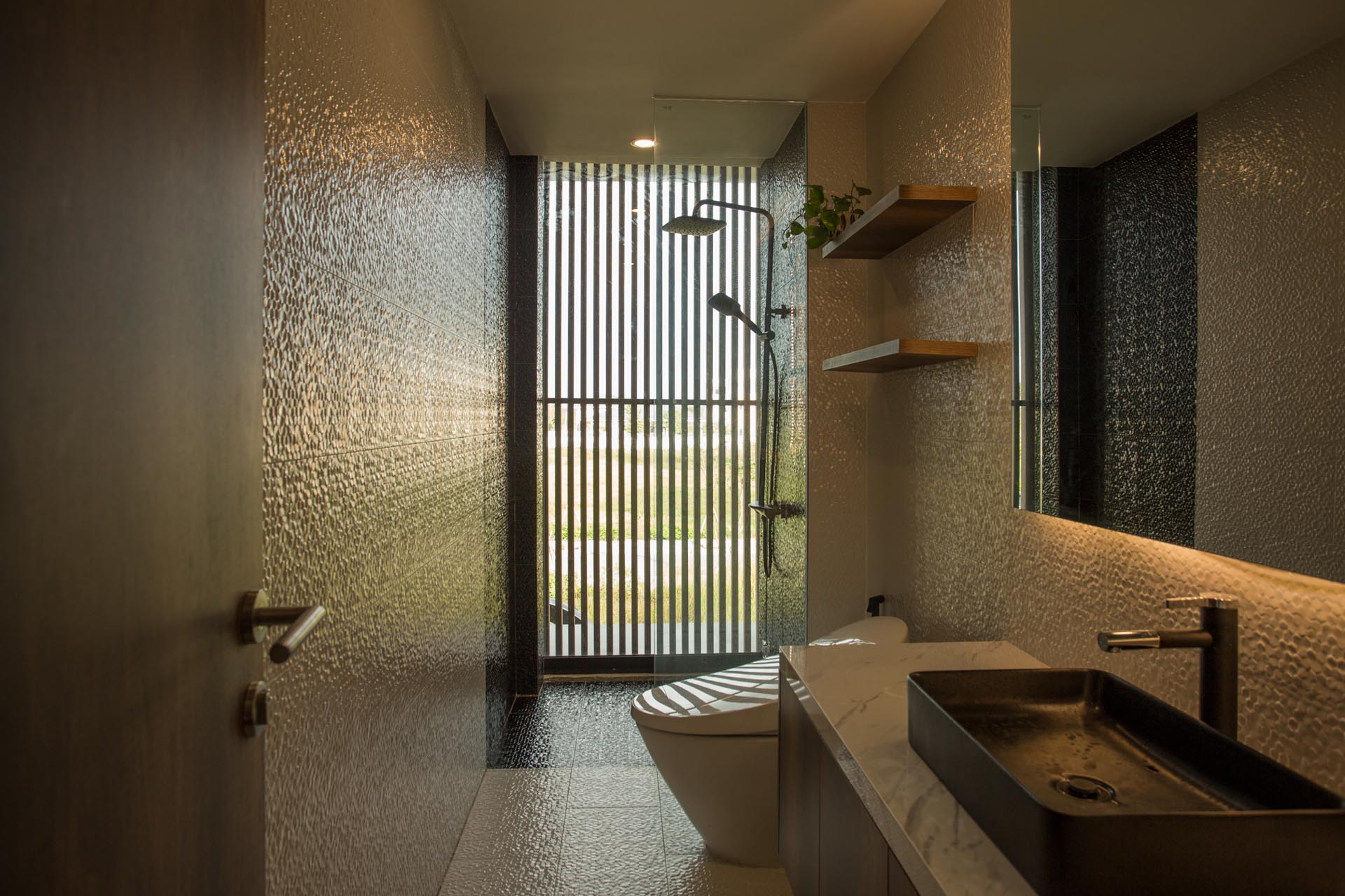 В современной ванной комнате стены и пол покрыты фактурной плиткой, а душевая кабина расположена у окна, откуда открывается вид на улицу.