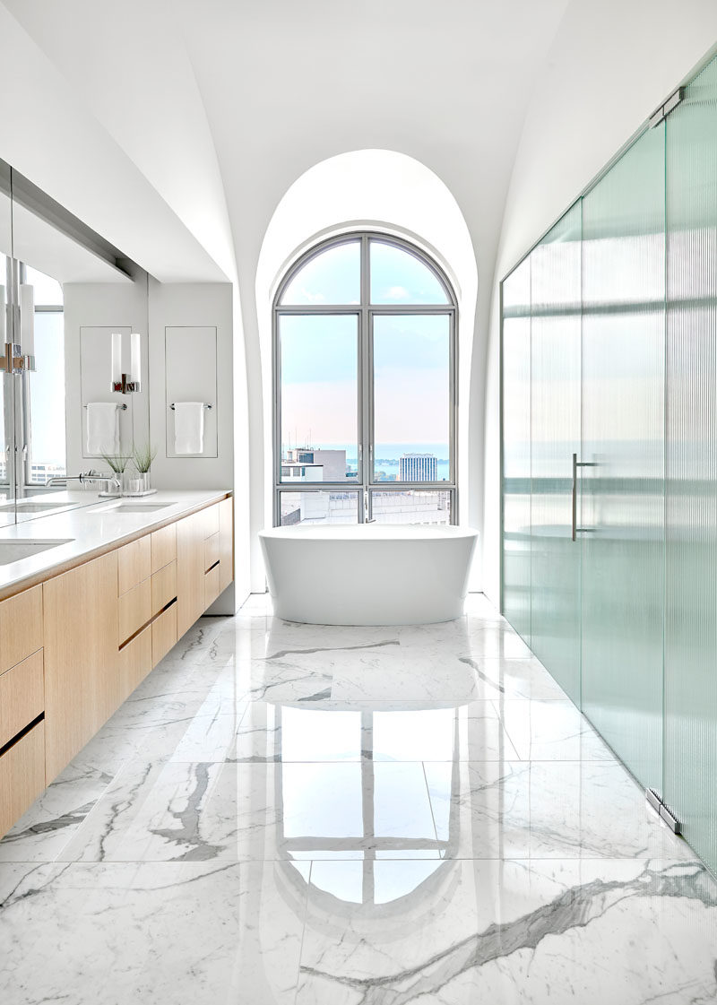 Идеи для ванных комнат - в этой главной ванной комнате отдельно стоящая ванна стоит прямо перед большим арочным окном, а большая туалетная бумага и зеркало украшают стену. # Современная ванная # Арочные окна # Дизайн ванной