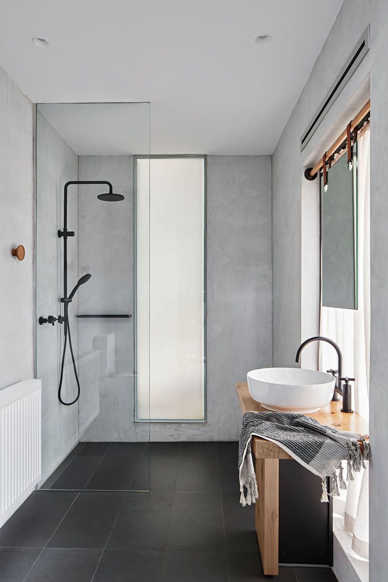 В Современная ванная комната зеркало перед окном висит на ремнях, прикрепленные к деревянному стержню, стеклянная перегородка для душа от пола до потолка отделяет душ от остальной части ванной комнаты. # Современная ванная # Дизайн ванной 