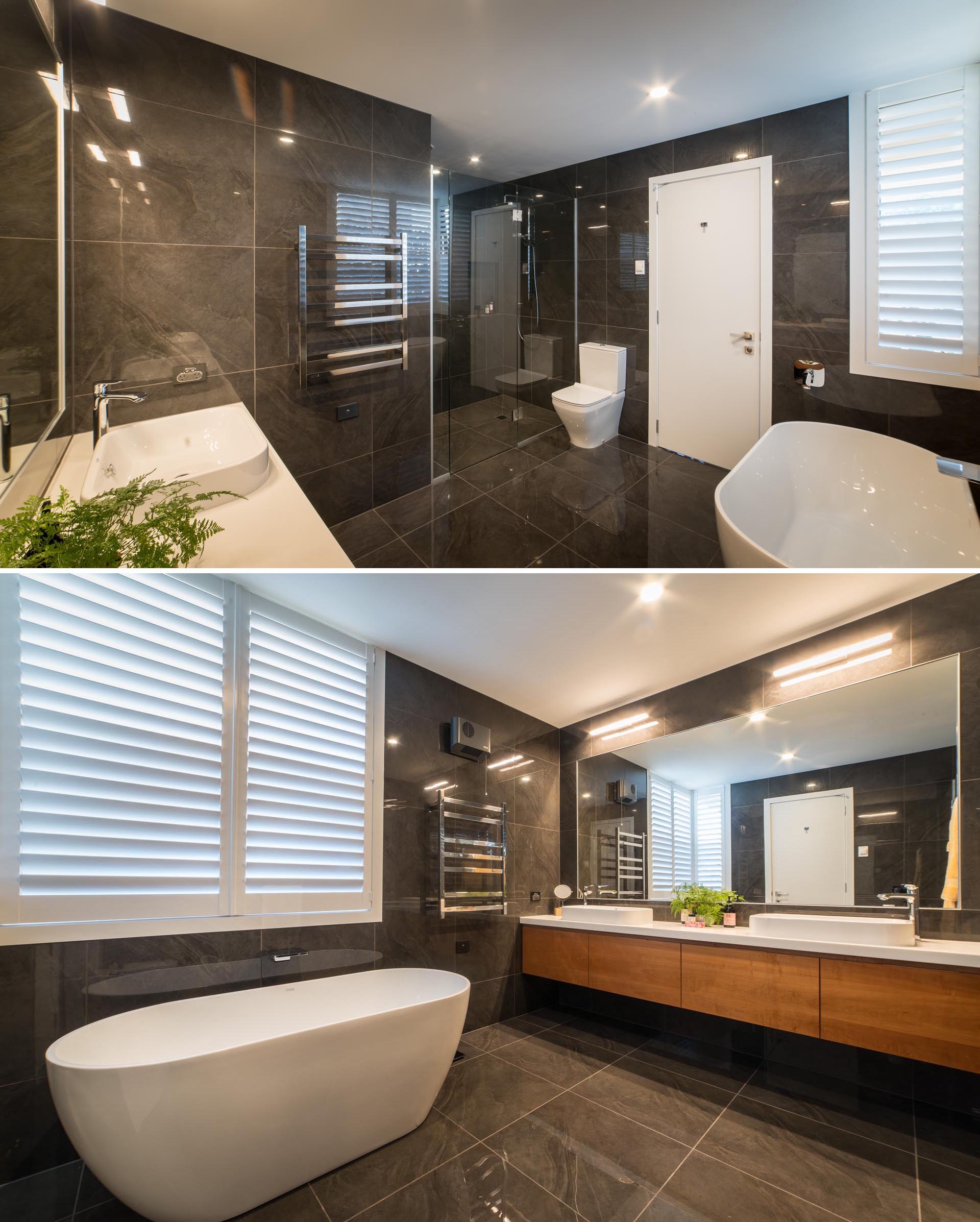 Современная главная ванная комната с крупноформатной плиткой темного цвета, покрывающей стены и пол, а также белая отдельно стоящая ванна и столешница, которые создают контрастный элемент.