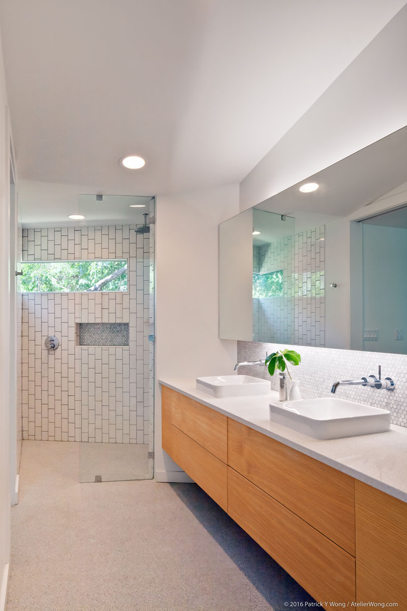 В этой современной ванной комнате есть большой туалетный столик с двойной раковиной и душевая кабина со стеклянной дверцей и белой плиткой. # Современная ванная # Дизайн ванной