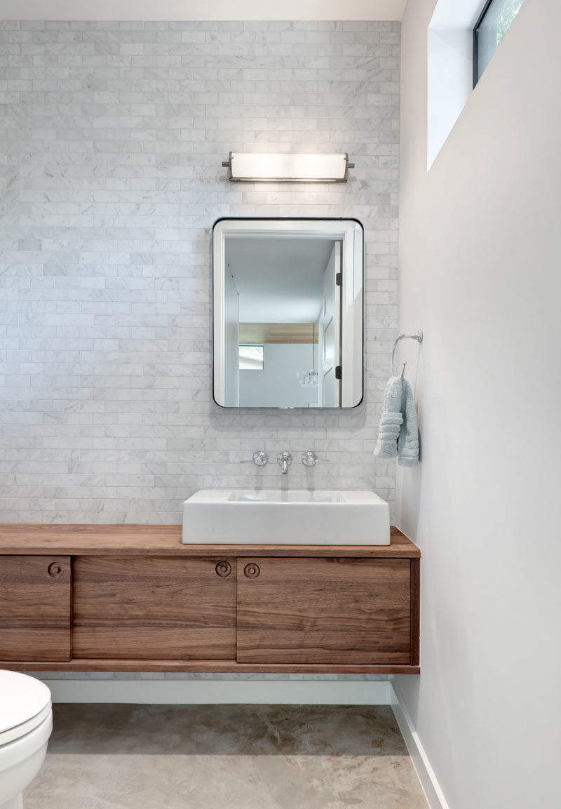 Идеи для ванных комнат - в этой современной ванной комнате светло-серая плитка покрывает стены, а простой парящий деревянный туалетный столик добавляет естественности. #BathroomIdeas # ModernBathroom #BathroomDesign