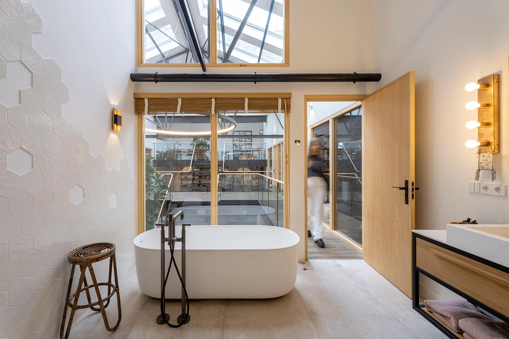 Современная ванная комната с шестиугольной плиткой и отдельно стоящей шляпой для ванны выходит на этаж ниже.