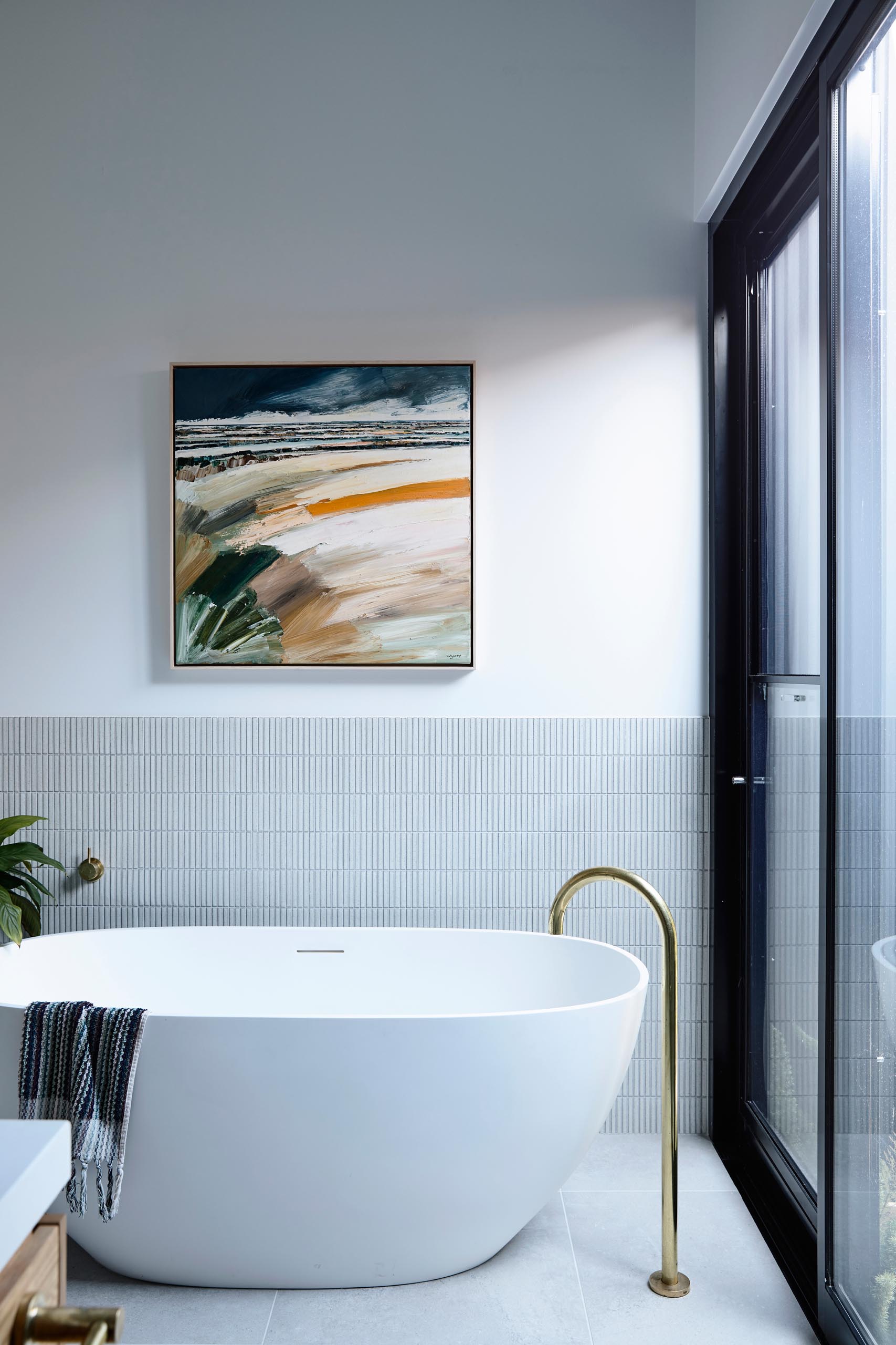 Современная ванная комната с отдельно стоящей белой ванной с вертикальным расположением фона из небольшой прямоугольной плитки.