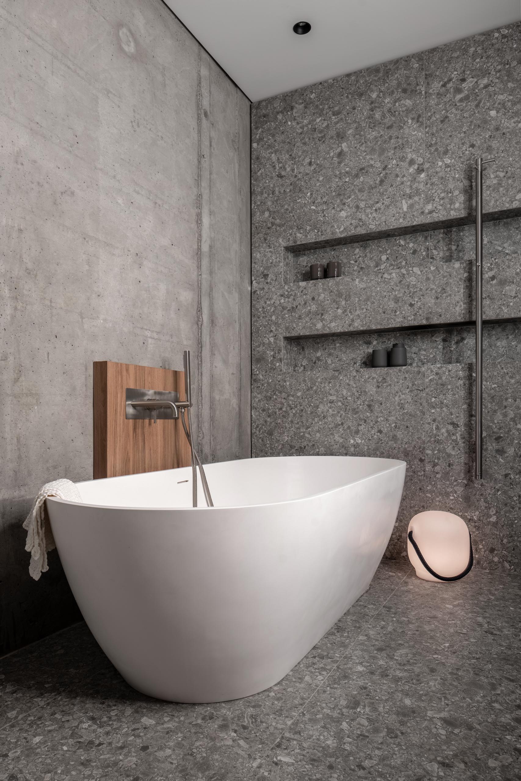 Современная ванная комната с отдельно стоящей белой ванной и душем со встроенными нишами для полок.