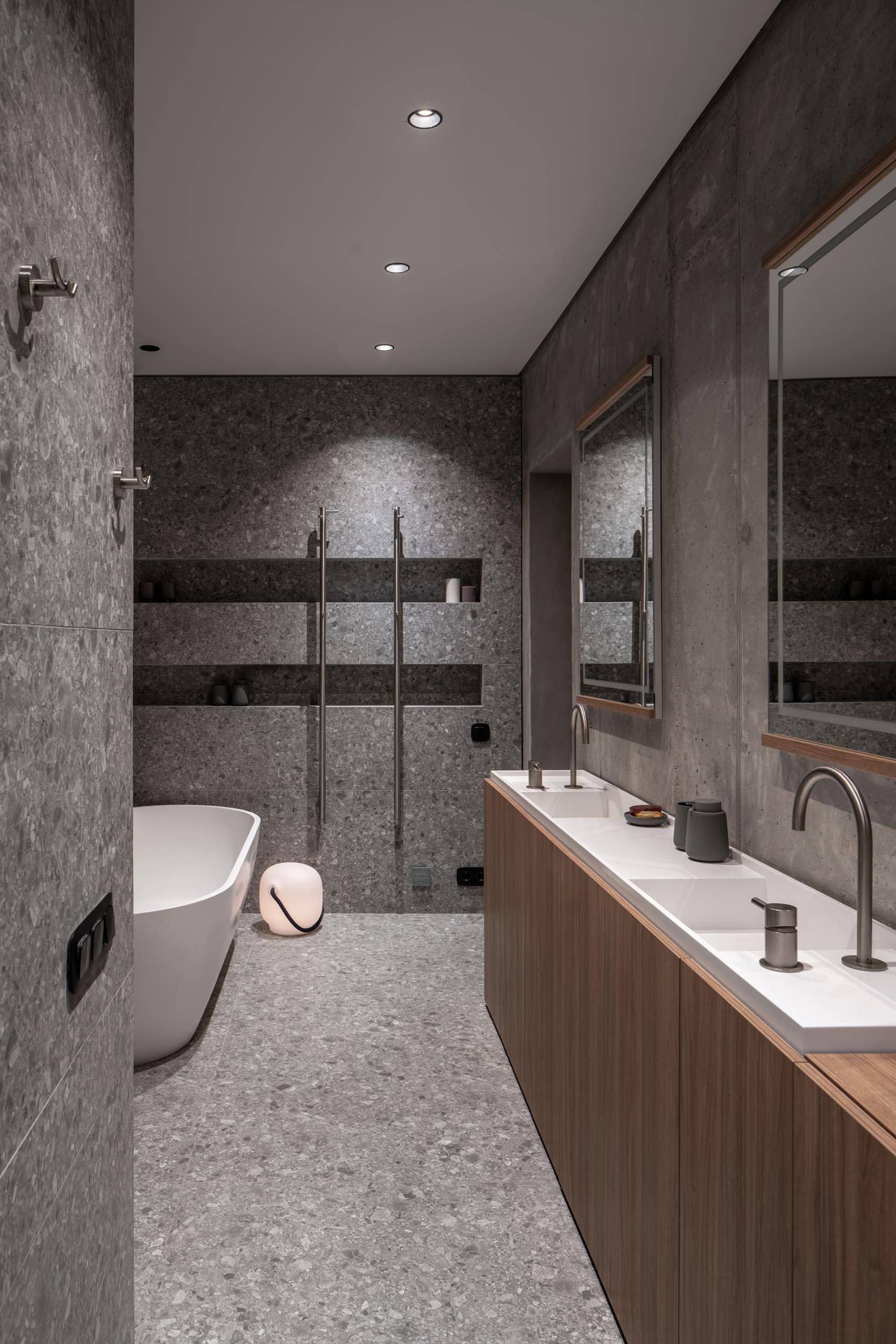 Современная ванная комната с узкой, изготовленной на заказ двойной раковиной, отдельно стоящей белой ванной и душем со встроенными нишами для душа.