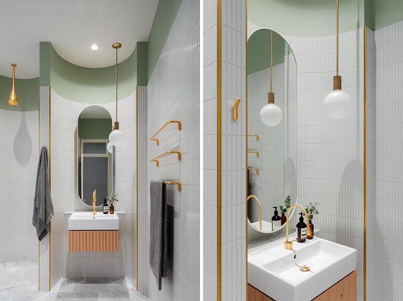 Современная ванная комната с изогнутыми стенами, облицованными плиткой, создает различные секции для умывальника и душа, а золотые акценты добавляют металлический оттенок.