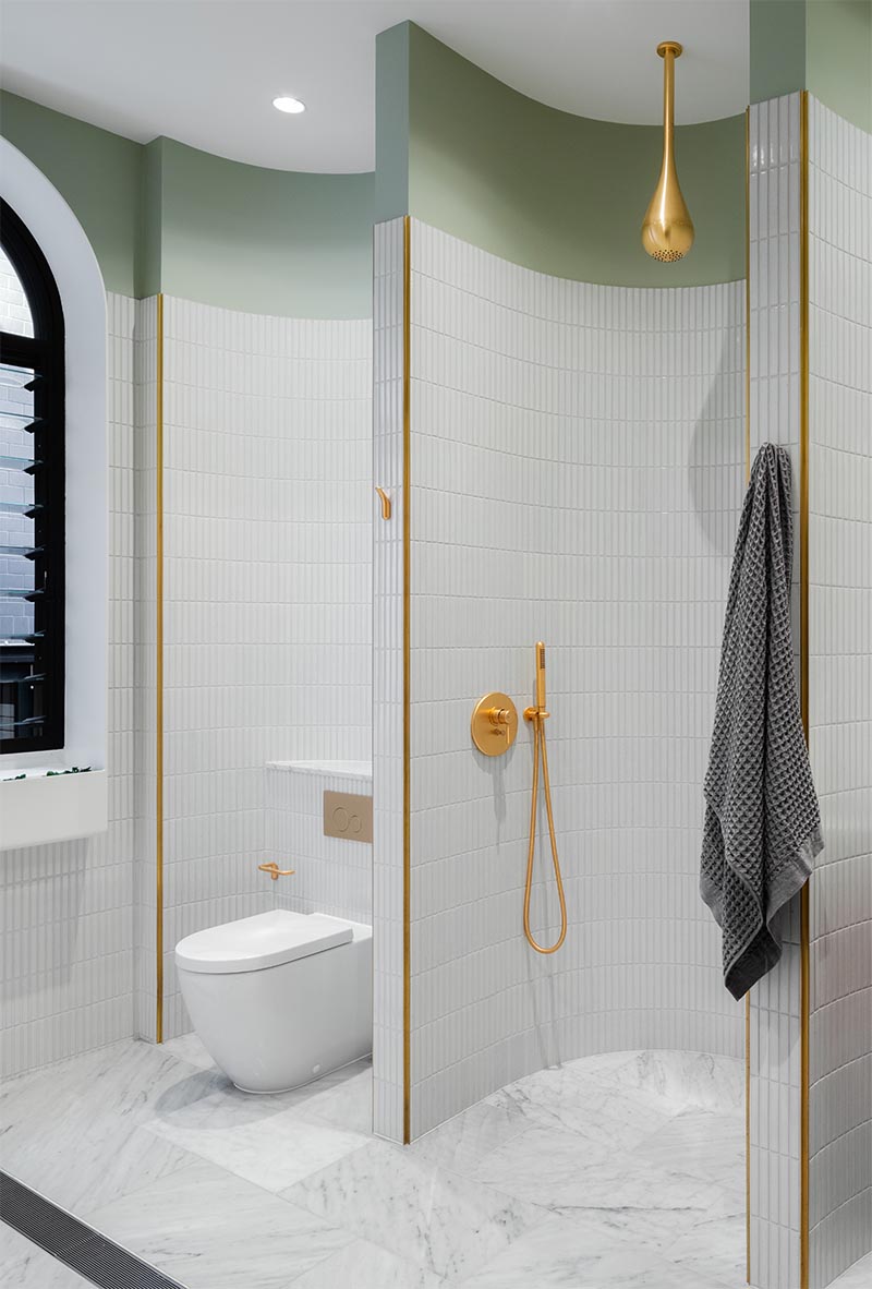 Современная ванная комната с изогнутыми стенами, облицованными плиткой, создает различные секции для умывальника, душа и туалета.