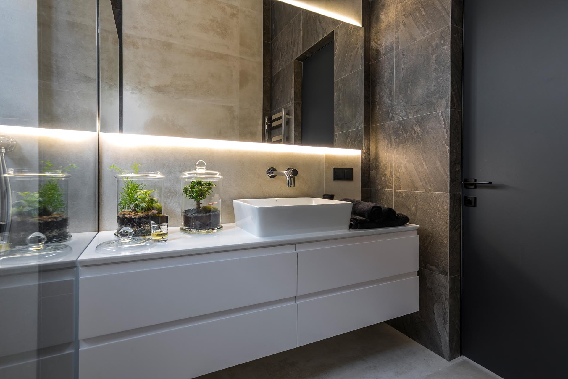 Современная ванная комната с белым туалетным столиком и зеркалом с подсветкой.