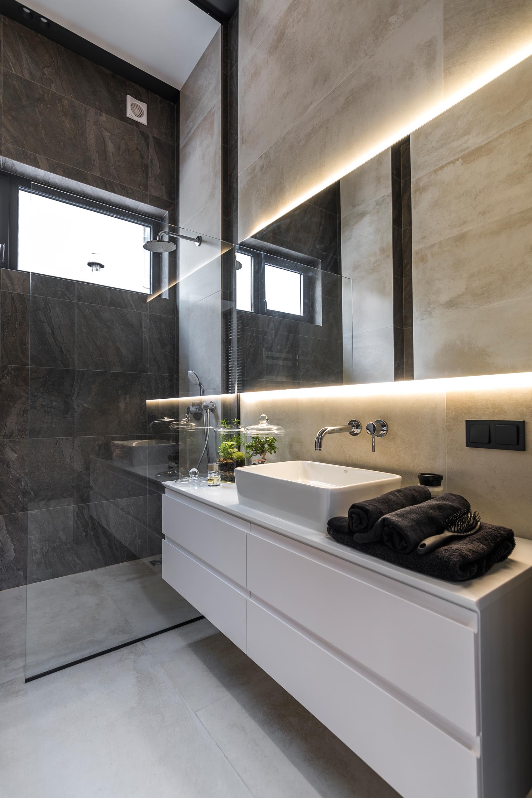Современная ванная комната с белым туалетным столиком и зеркалом с подсветкой.