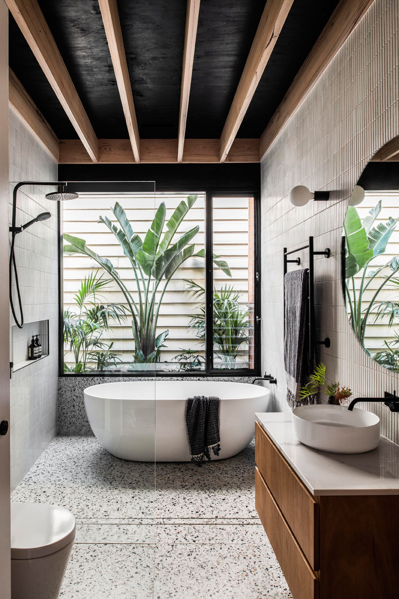 В ванной комнате стены покрыты плиткой, а отдельно стоящая ванна расположена под окном, а стеклянная душевая кабина в минималистском стиле позволяет естественному свету из окна проникать по всей комнате. # Современная ванная # Дизайн ванной # Плиточные стены
