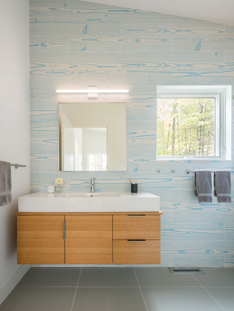 В этой современной ванной комнате плитка под дерево светло-голубого цвета создает уникальный и яркий акцент на стене. #ModernBathroom #AccentWall