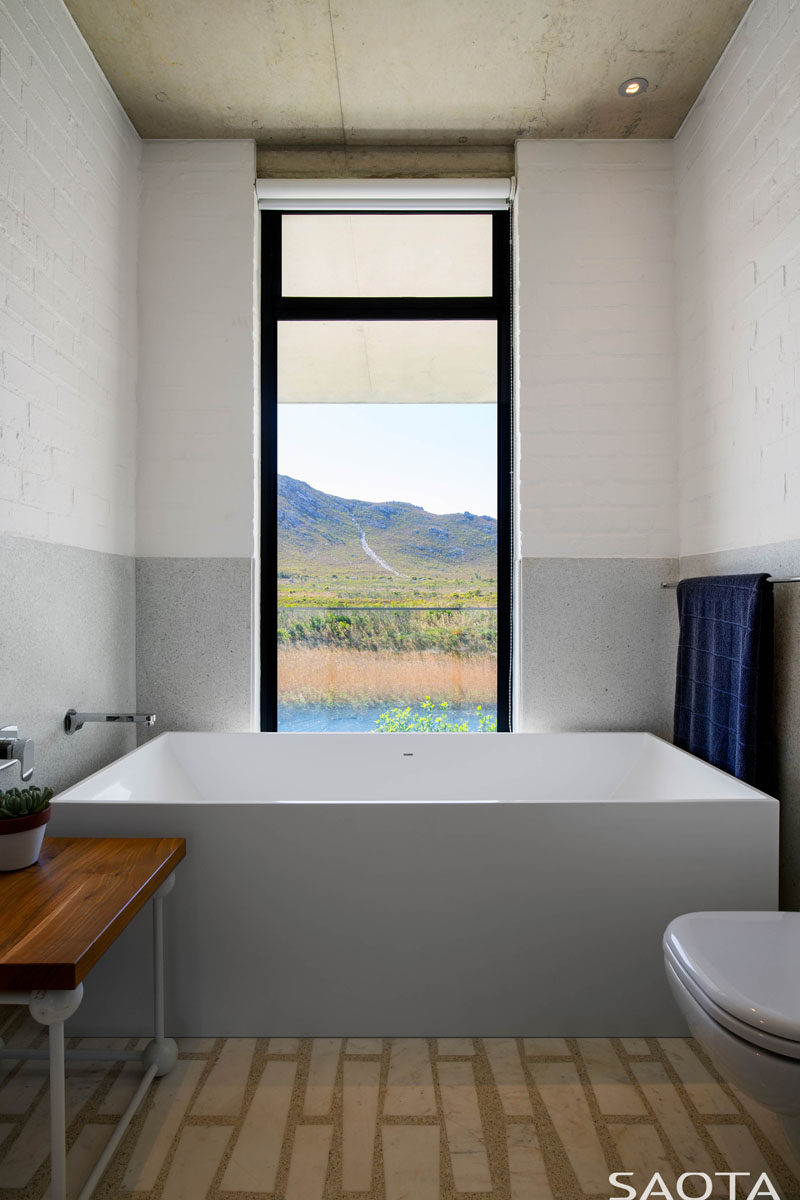 В этой современной ванной комнате ванная находится в конце комнаты, вертикальное окно обрамляет вид, словно произведение искусства. # Современная ванная # Дизайн ванной