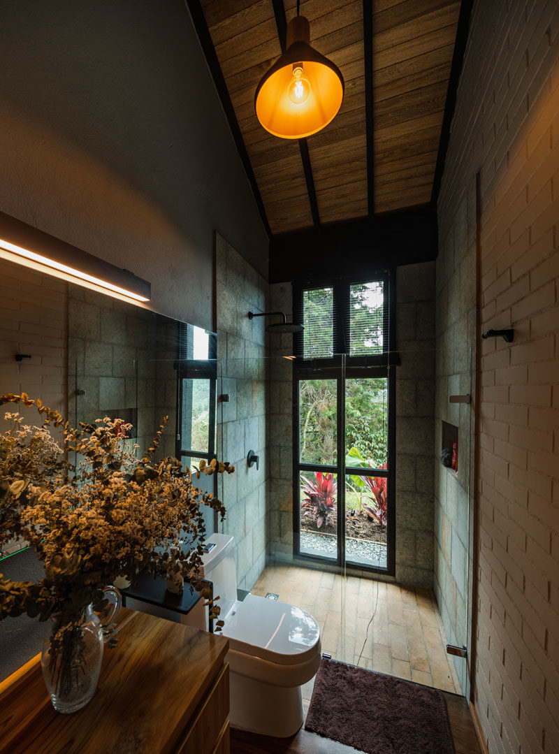 Идеи для ванных комнат - современная ванная комната с высокими потолками, душевой кабиной, расположенной рядом с окнами, и деревянным туалетным столиком. #BathroomIdeas #BathroomDesign