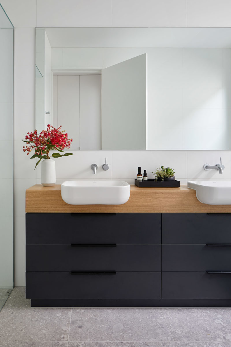 Идеи для ванных комнат - в этой современной ванной комнате черный и деревянный туалетный столик контрастирует с белыми стенами, а зеркало отражает свет во всем пространстве. #BathroomIdeas # ModernBathroom #BlackVanity