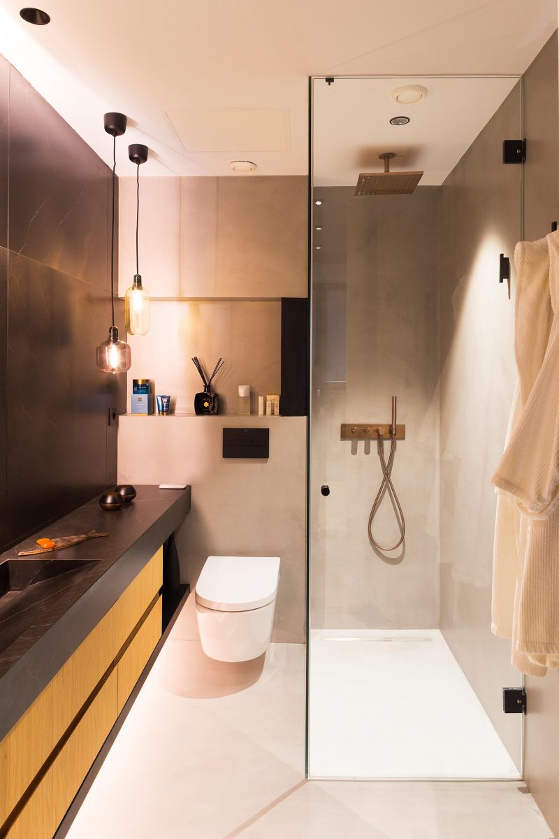 Современная ванная комната с черным и деревянным туалетным столиком, стеклянной душевой кабиной и красивым стеллажом.